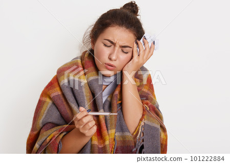 Young beautiful woman with dark hair wearing checkered blanket, posing over isolated white background, lady touching her forehead for illness and fever and cold, coronavirus sick. health care concept Young beautiful woman with dark hair wearing checkered blanket, posing over isolated white background, lady touching her forehead for illness and fever and cold, coronavirus sick. health care concept 101222884