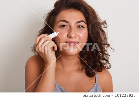 Sstudio shot of girl applying treatment cream from acne, charming smiling female wearing gray sleveless t shirt, having problem skin posing isolated overwhite studio background. Skin care concept. Sstudio shot of girl applying treatment cream from acne, charming smiling female wearing gray sleveless t shirt, having problem skin posing isolated overwhite studio background. Skin care concept. 101222923