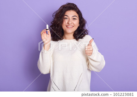 Close up portrait of female holds tampon over lilac background, having happy facial expression, shows ok sign, being glad with her choosing, has period, lady wears white shirt, wearing stylish outfit. Close up portrait of female holds tampon over lilac background, having happy facial expression, shows ok sign, being glad with her choosing, has period, lady wears white shirt, wearing stylish outfit. 101223081