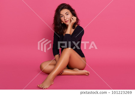 Full length body size photo of sitting on floor tender gorgeous attractive girl with great figure shape, isolated over rose background, keeping hand under chin. 101223269