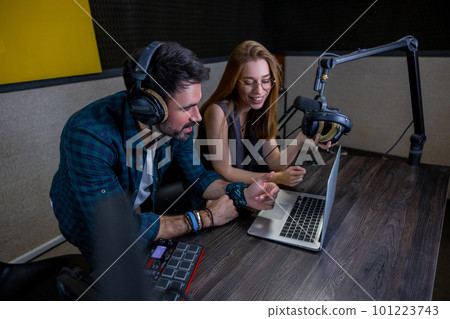 Two people sitting at the table and watching something on laptop Two people sitting at the table and watching something on laptop 101223743
