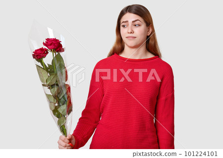 Horizontal shot of puzzled dark haired young Caucasian woman raises eyebrows, holds red roses, recieves bouquet from stranger, has suspicious facial expression, isolated over white background Horizontal shot of puzzled dark haired young Caucasian woman raises eyebrows, holds red roses, recieves bouquet from stranger, has suspicious facial expression, isolated over white background 101224101