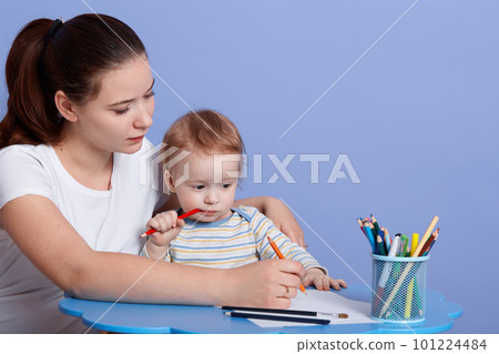 Close up portrait of little Caucasian boy sitting at table and drawing picture by colour pencil witg his mummy, mother teach her son painting, making present for dad. Art and creativity concept. 101224484