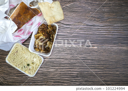 Chinese takeaway food selection in plastic bag. Bami, babi pangang, crispy shredded beef, sweet and sour chicken, krupuk top view on wooden table copy space. Food delivery Chinese takeaway food selection in plastic bag. Bami, babi pangang, crispy shredded beef, sweet and sour chicken, krupuk top view on wooden table copy space. Food delivery 101224994