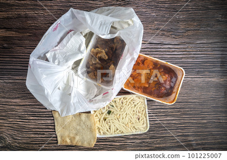Chinese takeaway food selection in plastic bag. Bami, babi pangang, crispy shredded beef, sweet and sour chicken, krupuk top view on wooden table copy space. Food delivery Chinese takeaway food selection in plastic bag. Bami, babi pangang, crispy shredded beef, sweet and sour chicken, krupuk top view on wooden table copy space. Food delivery 101225007