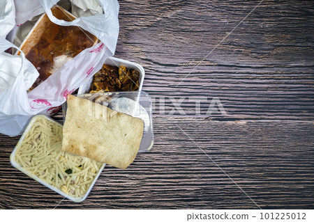 Chinese takeaway food selection in plastic bag. Bami, babi pangang, crispy shredded beef, sweet and sour chicken, krupuk top view on wooden table copy space. Food delivery Chinese takeaway food selection in plastic bag. Bami, babi pangang, crispy shredded beef, sweet and sour chicken, krupuk top view on wooden table copy space. Food delivery 101225012