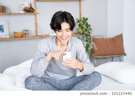 年輕人在床上觀看智能手機 101225440