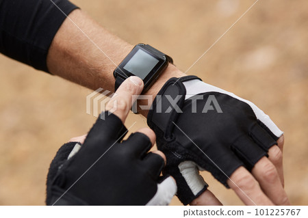 Runner using monitor training running, smartwatch checking performance, GPS. There are sportgloves, finger touching screen, using new technologies during training. People and technologies concept. 101225767