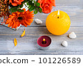 Flat lay still life with orange flowers, lit candles and pebbles 101226589