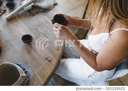 A potter woman sculpts clay at a table. Top view. A potter woman sculpts clay at a table. Top view. 101229323