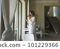 A young woman smokes a cigarette and drinks coffee while looking 101229366