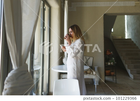 A young woman smokes a cigarette and drinks coffee while looking 101229366