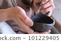 a woman processes a clay bowl with tools. 101229405