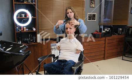 a man with disabilities gets his hair cut and styled in a barber shop. 101229454