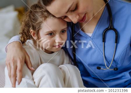 Young doctor hugging little girl in hospital room. 101231396