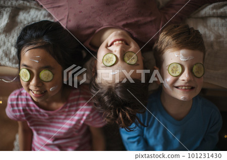 Top view of three happy friends lying in a bed with beauty mask on face. Top view of three happy friends lying in a bed with beauty mask on face. 101231430