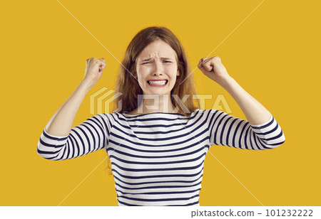 Young sad confused frustrated woman in trouble clenches her fists in despair on yellow background. 101232222