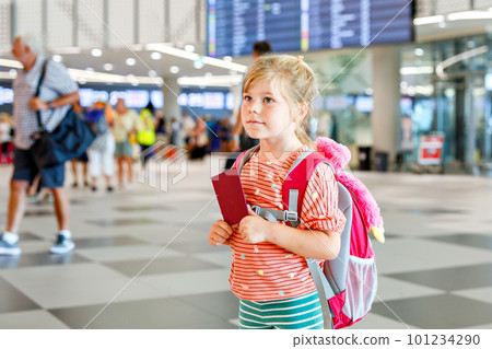 Little preschool girl at airport terminal. Happy child going on vacations by airplane. Smiling kid with passport and bag. 101234290