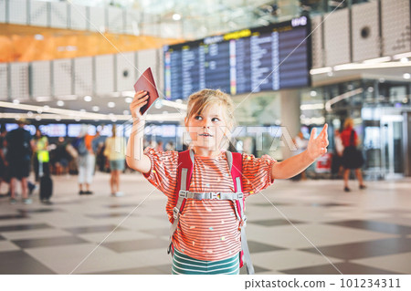 Little preschool girl at airport terminal. Happy child going on vacations by airplane. Smiling kid with passport and bag. Little preschool girl at airport terminal. Happy child going on vacations by airplane. Smiling kid with passport and bag. 101234311