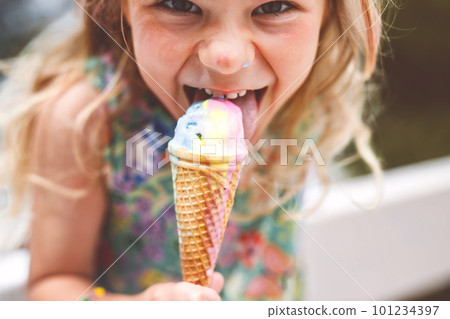 Happy preschool girl eating colorful ice cream in waffle cone on sunny summer day. Little toddler child eat icecream dessert. Sweet food on hot warm summertime days. Bright light, colorful ice-cream 101234397