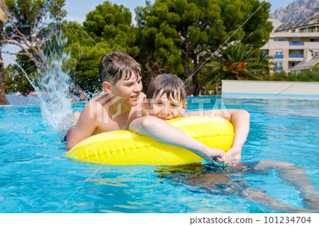 Two kids boys having fun on inflatable rubber rings in outdoor pool. Summer holiday. Summertime kids weekend. Children having fun, brothers on family vacations. Two kids boys having fun on inflatable rubber rings in outdoor pool. Summer holiday. Summertime kids weekend. Children having fun, brothers on family vacations. 101234704