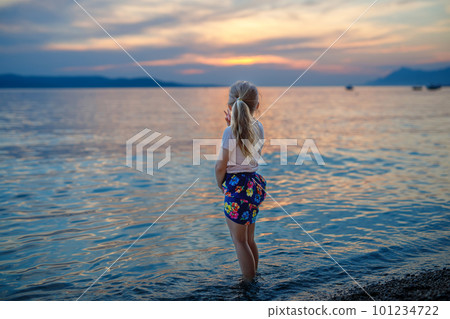 Little girl walking on beautiful ocean beach. Happy preschool child play by sunset on sea beach. Family vacations with children in summer. 101234722