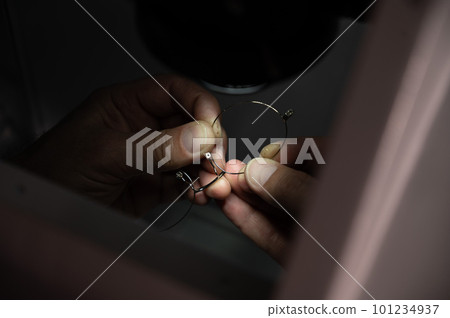 The technician solders the metal frame of the glasses. The technician solders the metal frame of the glasses. 101234937