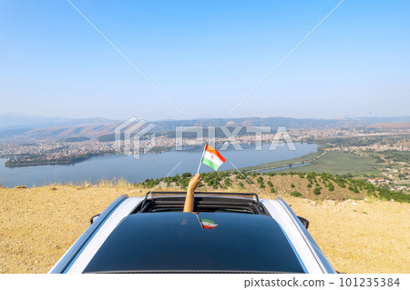 Woman holding Iran flag from the open car sunroof, window driving along the serpentine road in the mountains. Top view. Concept Woman holding Iran flag from the open car sunroof, window driving along the serpentine road in the mountains. Top view. Concept 101235384