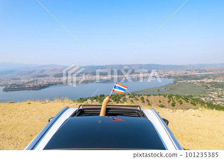 Woman holding Thailand flag from the open car sunroof, window driving along the serpentine road in the mountains. Top view. Concept Woman holding Thailand flag from the open car sunroof, window driving along the serpentine road in the mountains. Top view. Concept 101235385