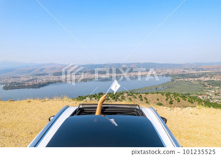 Woman holding Cyprus flag from the open car sunroof,  window driving along the serpentine road in the mountains. Top view. Concept 101235525