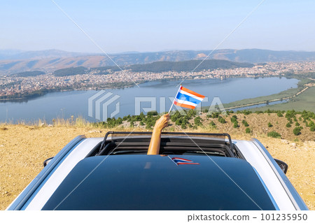 Woman holding Thailand flag from the open car sunroof, window driving along the serpentine road in the mountains. Top view. Concept Woman holding Thailand flag from the open car sunroof, window driving along the serpentine road in the mountains. Top view. Concept 101235950