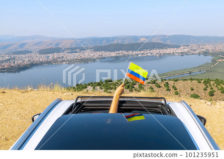 Woman holding Colombia flag from the open car sunroof, window driving along the serpentine road in the mountains. Top view. Concept Woman holding Colombia flag from the open car sunroof, window driving along the serpentine road in the mountains. Top view. Concept 101235951