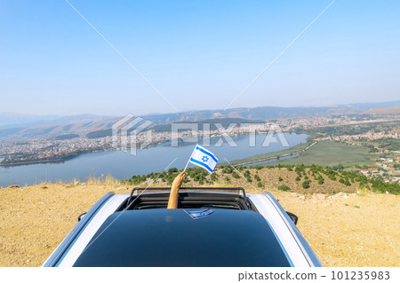 Woman holding  Israel flag from the open car sunroof,  window driving along the serpentine road in the mountains. Top view. Concept 101235983