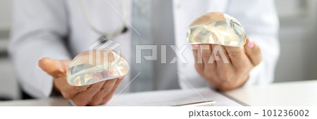 Female plastic surgeon holding silicone implants in hands. 101236002