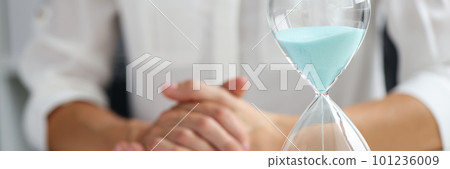 Businesswoman and sandglass on table in office Businesswoman and sandglass on table in office 101236009
