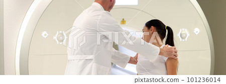 Doctor helping patient lie down for mri procedure 101236014