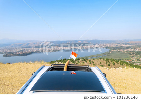 Woman holding Singapore flag from the open car sunroof, window driving along the serpentine road in the mountains. Top view. Concept Woman holding Singapore flag from the open car sunroof, window driving along the serpentine road in the mountains. Top view. Concept 101236146