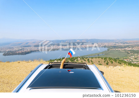 Woman holding Russia flag from the open car sunroof, window driving along the serpentine road in the mountains. Top view. Concept Woman holding Russia flag from the open car sunroof, window driving along the serpentine road in the mountains. Top view. Concept 101236150