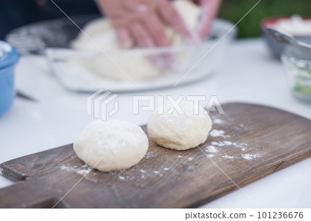 Close up of old female cook taking, holding dough, putting on wooden board, dusting with flour. Concept of fast food. Close up of old female cook taking, holding dough, putting on wooden board, dusting with flour. Concept of fast food. 101236676