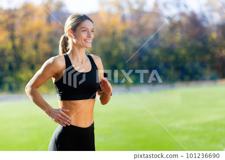 Female athlete is running in the stadium on a sunny day, woman in sportswear is active. Female athlete is running in the stadium on a sunny day, woman in sportswear is active. 101236690