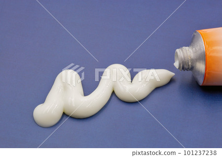 White paste squeezed out of a tube closeup on blue White paste squeezed out of a tube closeup on blue 101237238
