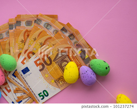 Easter concept with Euro banknotes and colorful eggs on pink background. Easter concept with Euro banknotes and colorful eggs on pink background. 101237274