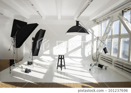 Professional lighting equipment, flashes, c-stands on a cyclorama in modern photo studio with a huge windows. Octabox, stripbox, softbox, buety plate and other stuff for photography. 101237696
