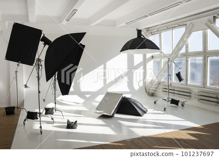 Professional lighting equipment, flashes, c-stands on a cyclorama in modern photo studio with a huge windows. Octabox, stripbox, softbox, buety plate and other stuff for photography. 101237697