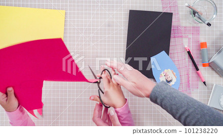 Flat lay. Little girl making a handmade Father's Day card from construction paper. 101238220