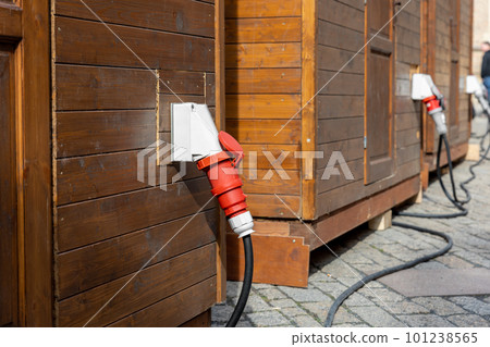Row of small wooden cabins city street with industrial high voltage wall-mounted sockets electric cabel. Temporary energy 380v waterptoof power supply connector adapter. Rental equipment construction Row of small wooden cabins city street with industrial high voltage wall-mounted sockets electric cabel. Temporary energy 380v waterptoof power supply connector adapter. Rental equipment construction 101238565