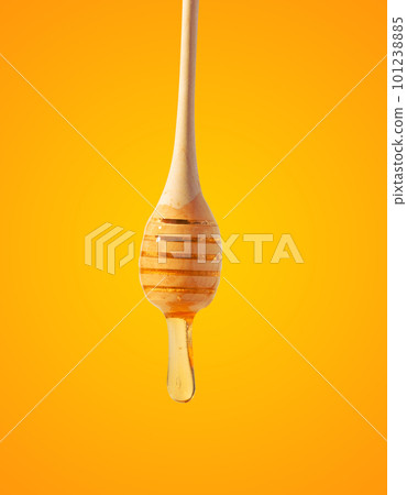Flowing drops of yellow honey from a wooden stick on a yellow background Flowing drops of yellow honey from a wooden stick on a yellow background 101238885