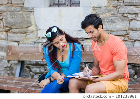 mixed race couple together in Villanueva Asturias writing on travel diary book outdoor on holiday  101238961
