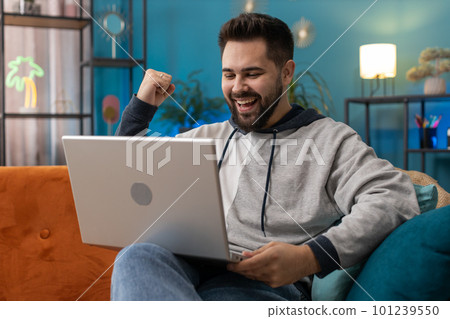 Amazed young man use laptop computer, receive good news message, shocked by victory, celebrate win 101239550