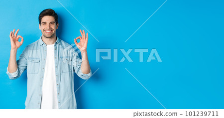 Confident smiling adult man, showing ok signs and looking pleased, like something, standing against blue background Confident smiling adult man, showing ok signs and looking pleased, like something, standing against blue background 101239711